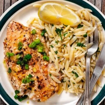 Pan seared tilefish with lemon butter, green onions, and orzo pasta on a dinner plate.