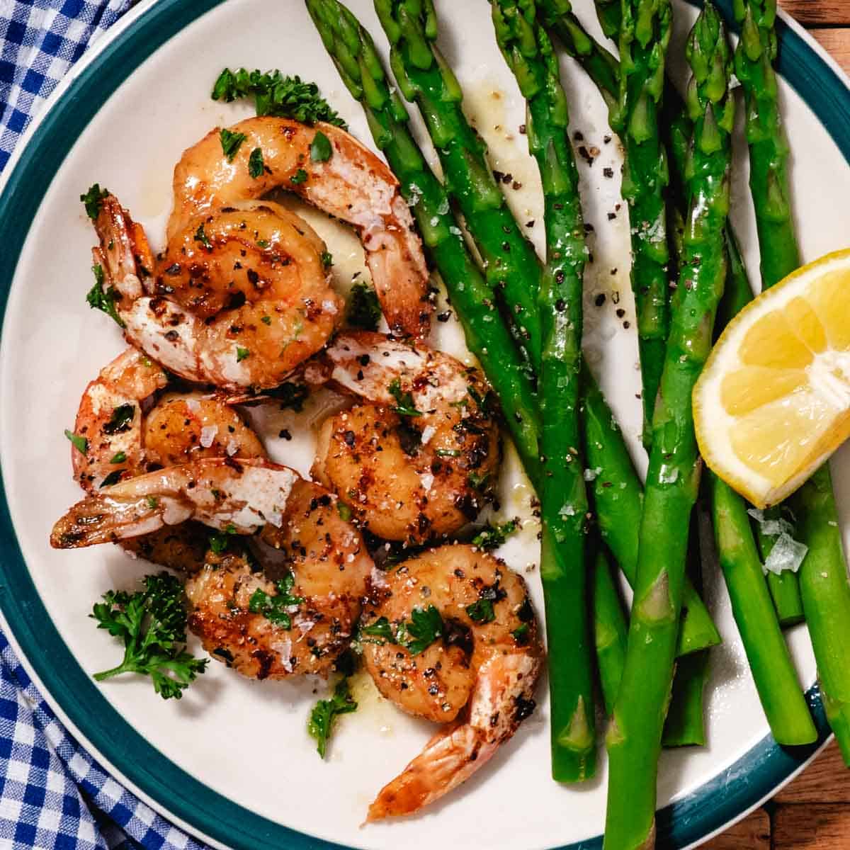 seared shrimp with asparagus and a lemon wedge.