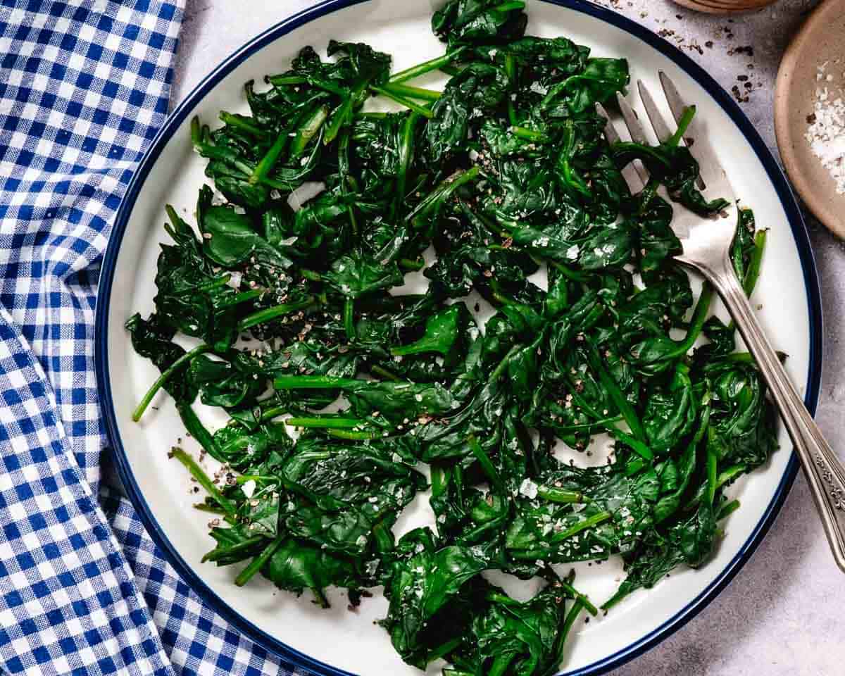 plate of steamed spinach seasoned with salt and pepper.