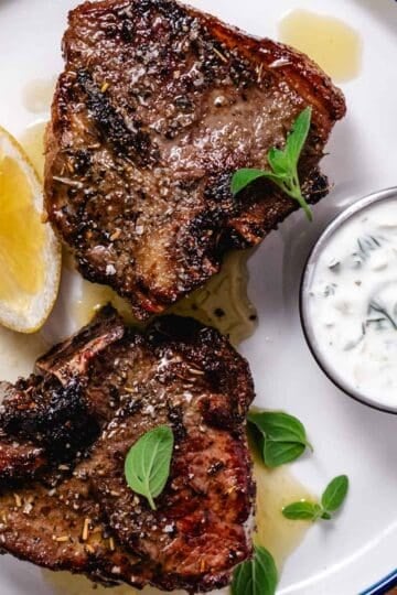 Air fryer lamb loin chops served with tzatziki and lemon wedges