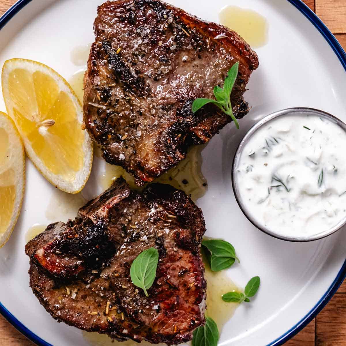 Air fryer lamb loin chops served with tzatziki and lemon wedges