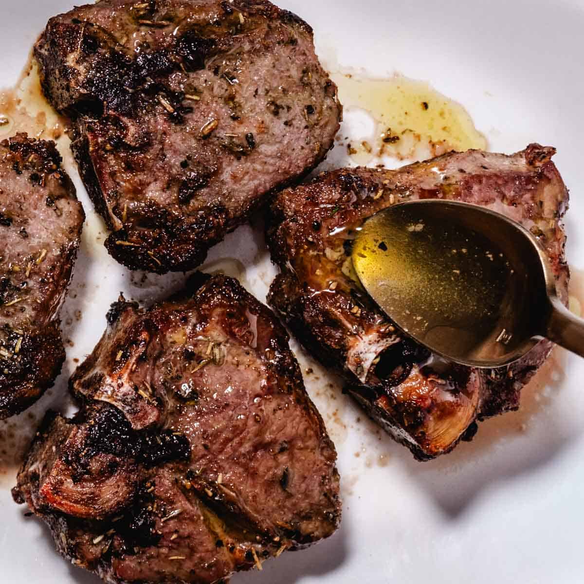 Air fryer lamb chops being basted with garlic butter