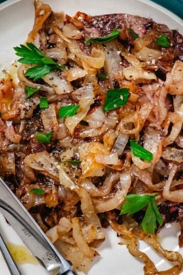 Baked beef liver and onions plated with caramelized onions and fresh parsley on a white dish, easy high protein dinner recipe