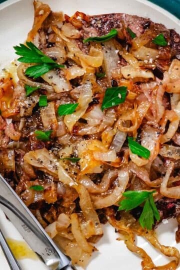 Baked beef liver and onions plated with caramelized onions and fresh parsley on a white dish, easy high protein dinner recipe