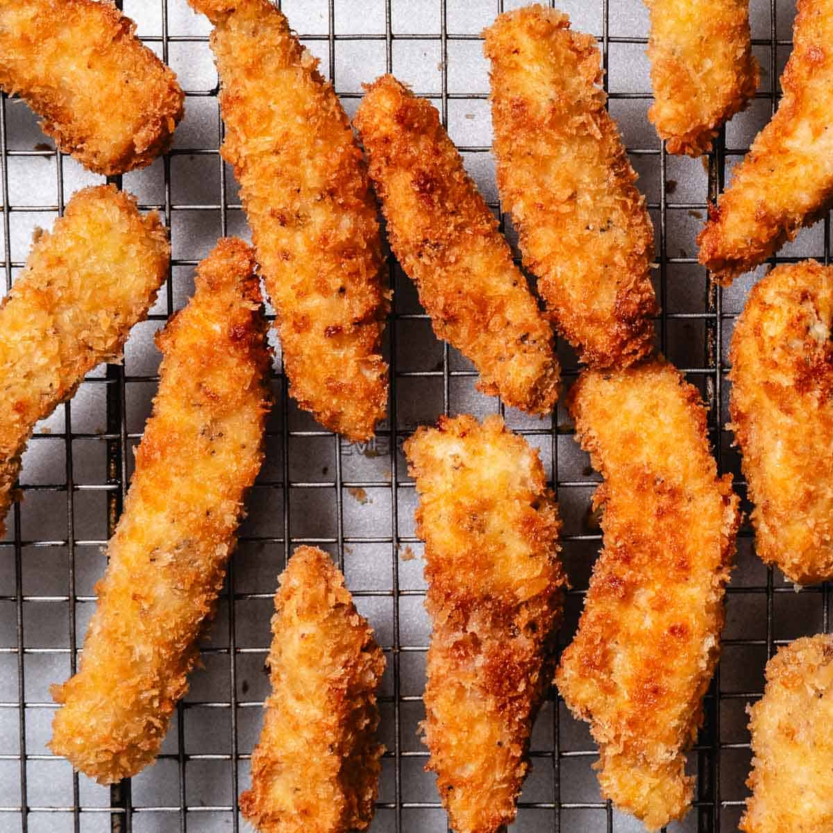 Crispy golden panko chicken strips draining on a wire rack.