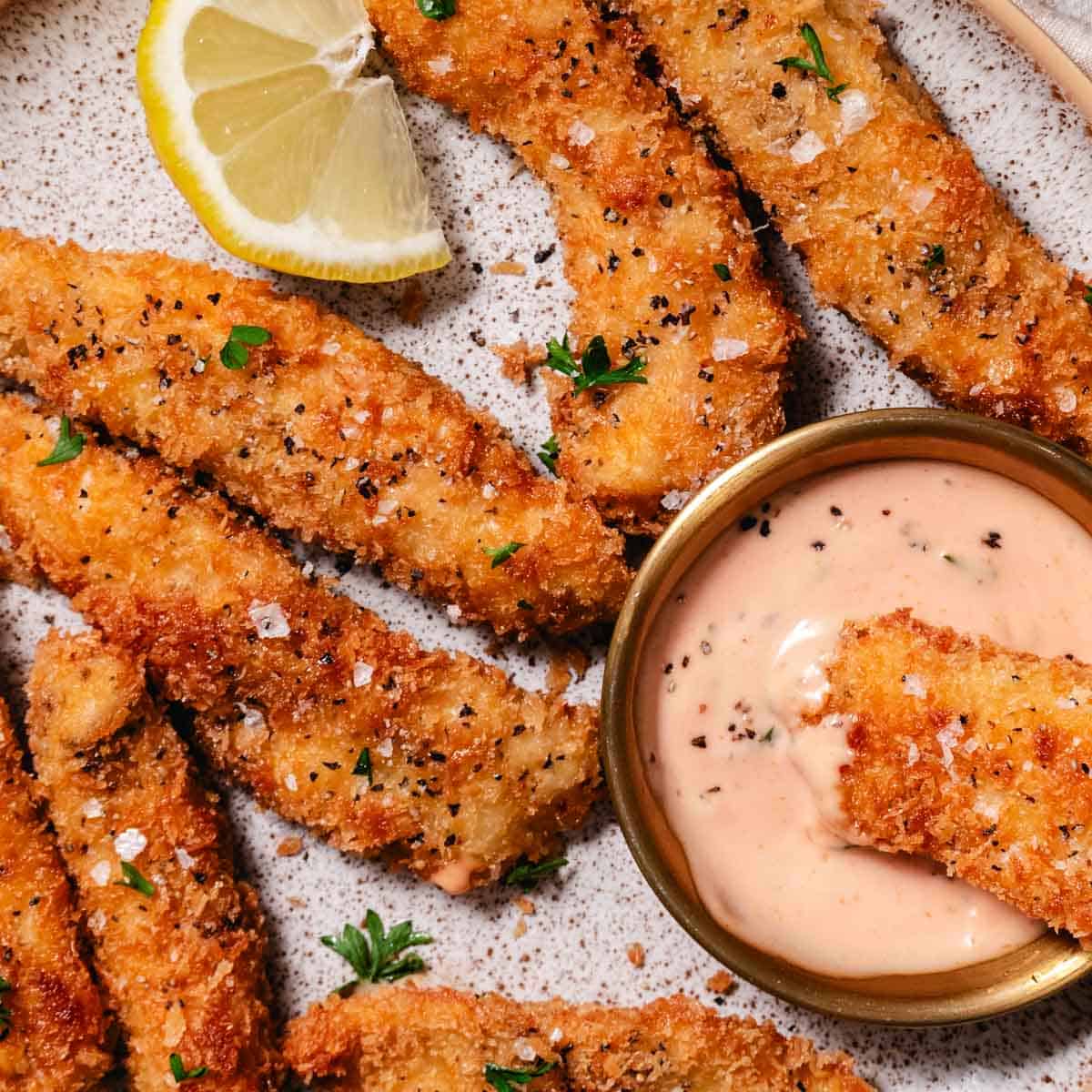 mayo ketchup sauce served with crispy chicken strips with one strip dipped in the creamy sauce