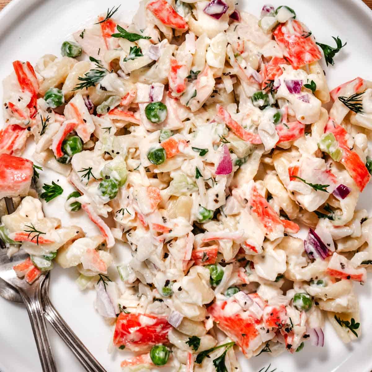 Close up of shrimp and crab salad with pasta, peas, and creamy lemon dressing on a spoon