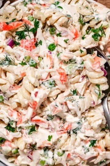 Close up of shrimp and crab salad with pasta, peas, and creamy lemon dressing on a spoon