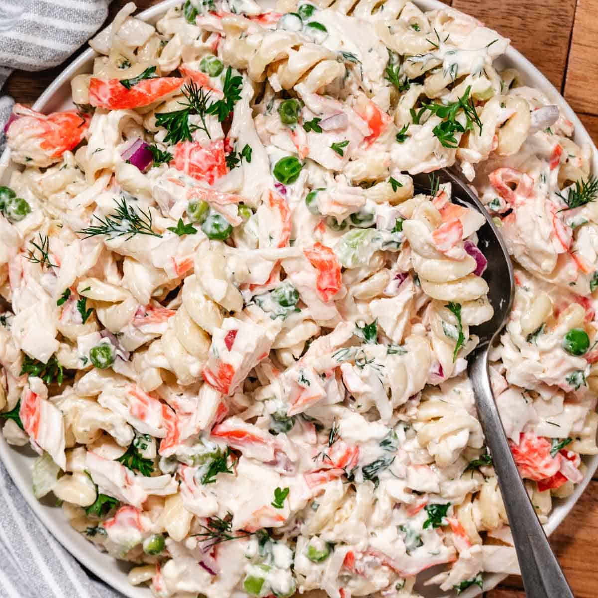 Close up of shrimp and crab salad with pasta, peas, and creamy lemon dressing on a spoon