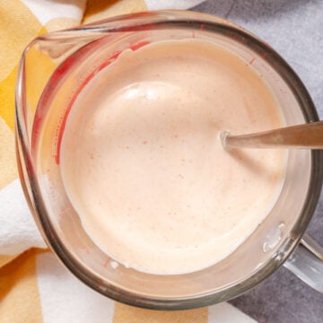 creamy taco sauce in measuring cup with spoon, smooth and ready to serve