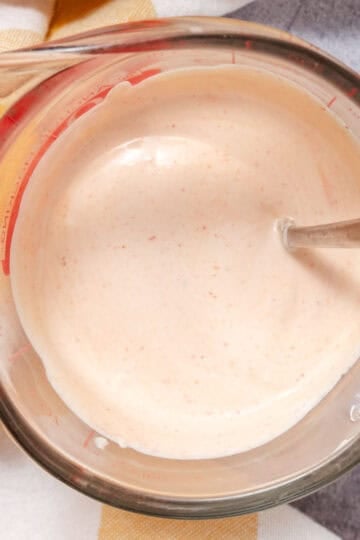 creamy taco sauce in measuring cup with spoon, smooth and ready to serve