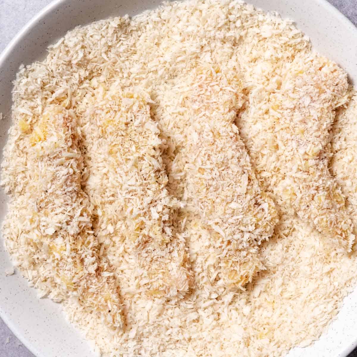 Chicken strips completely coated with panko breadcrumbs.