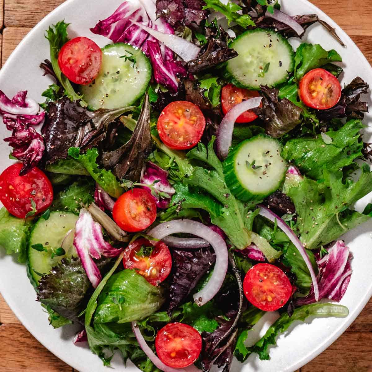simple garden salad with olive oil dressing mixed greens tomatoes cucumber and red onion