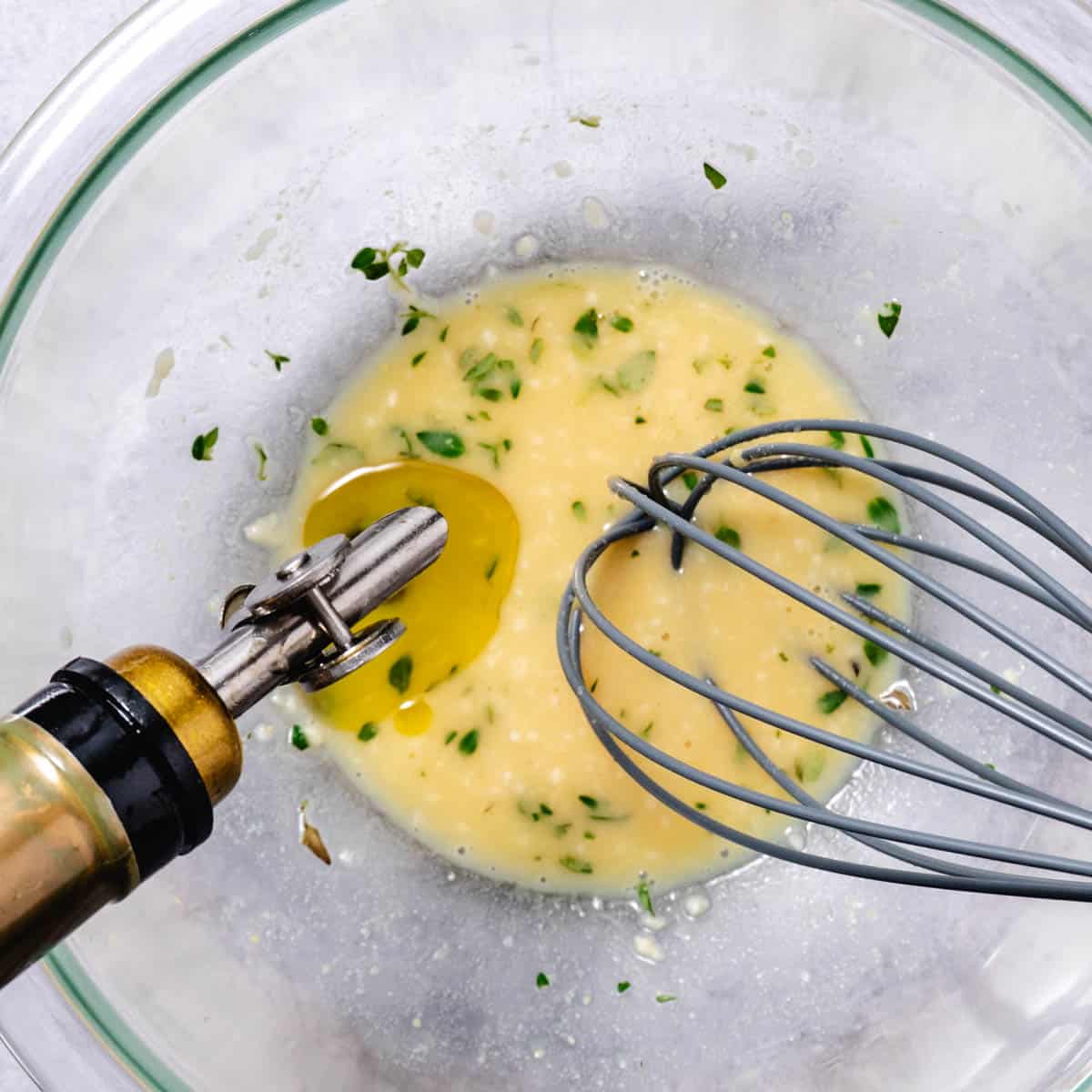 lemon dijon vinaigrette being whisked with olive oil in a glass bowl