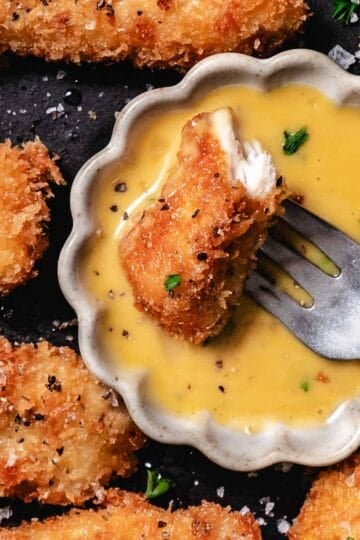 chicken nugget dipped in creamy honey mustard sauce with fork on plate
