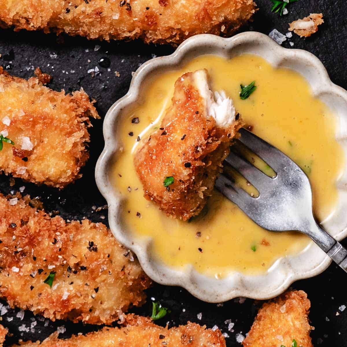 chicken nugget dipped in creamy honey mustard sauce with fork on plate