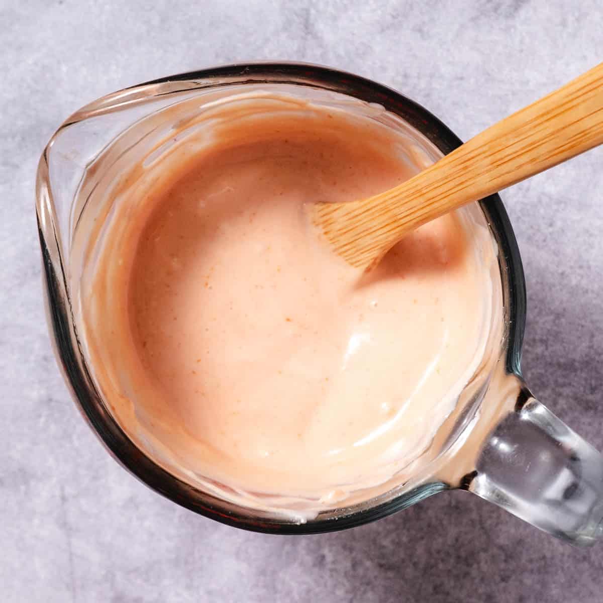 mayo ketchup sauce being mixed in a glass measuring cup until smooth and creamy