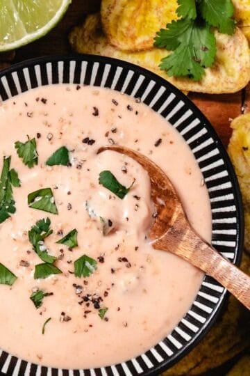 mayo ketchup sauce served in a bowl with fried plantains and lime wedges on a wooden board