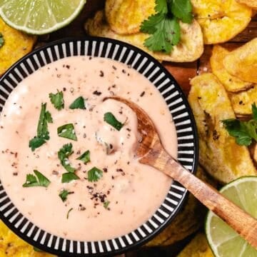 mayo ketchup sauce with spoon scooping creamy dipping sauce served with fried plantains and lime wedges