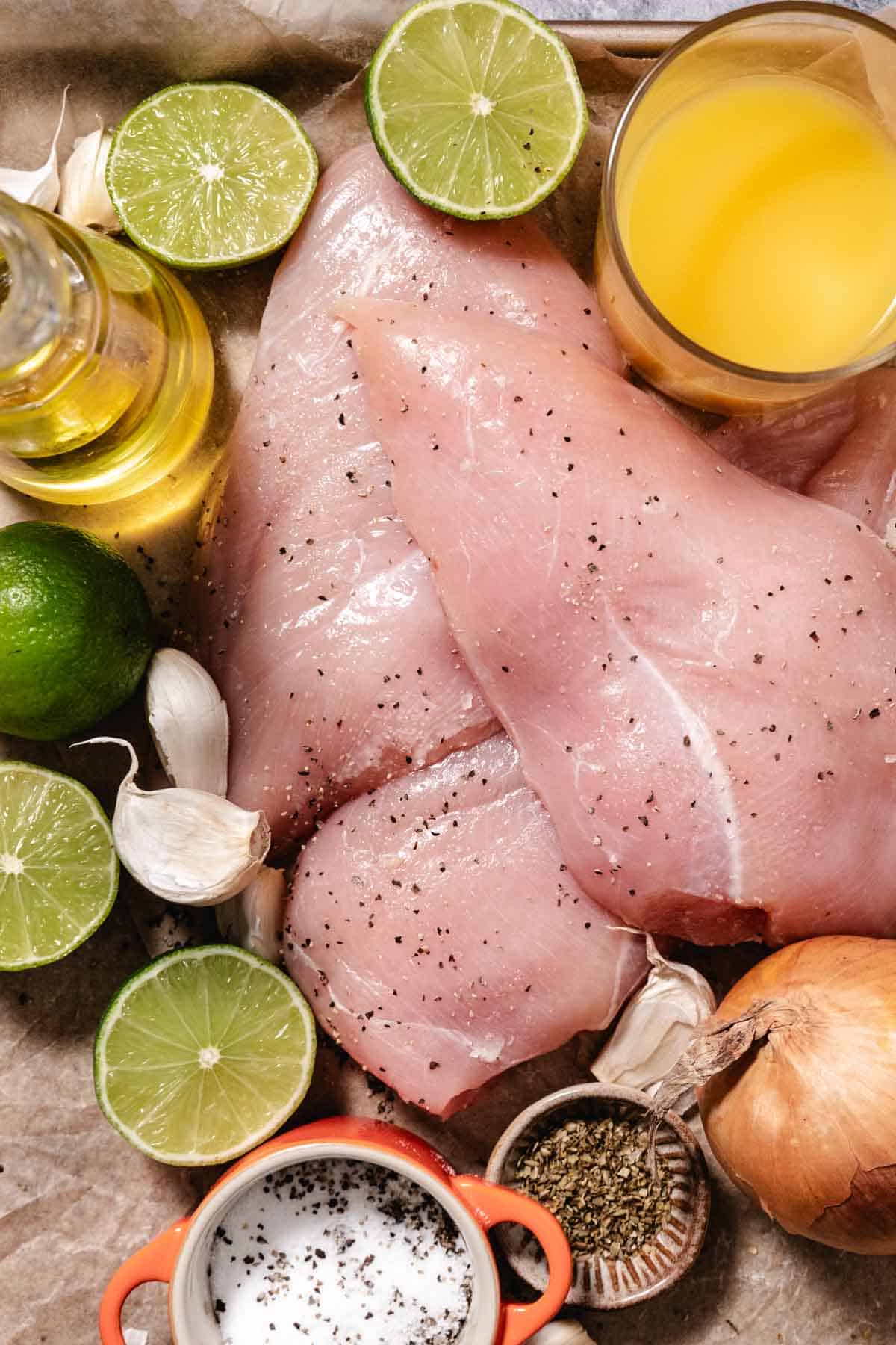 Raw chicken breasts with lime, orange juice, garlic, onion, and spices for mojo marinade