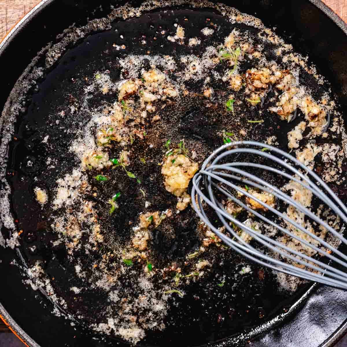 whisking butter and garlic in skillet for steak