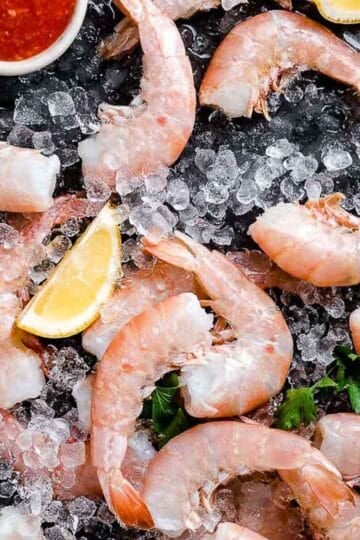 raw shrimp on ice with lemon wedges and cocktail sauce