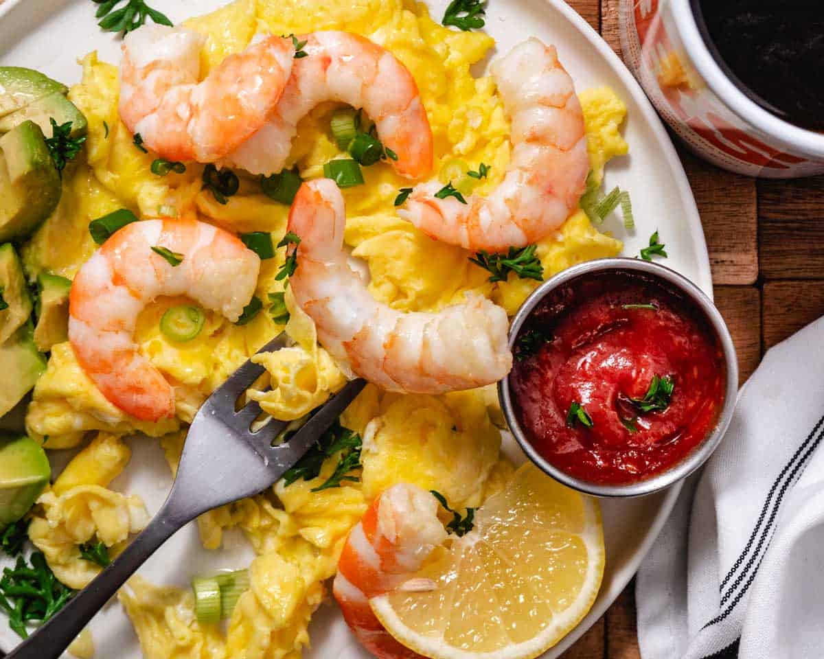 shrimp scrambled eggs with avocado and a side of cocktail sauce