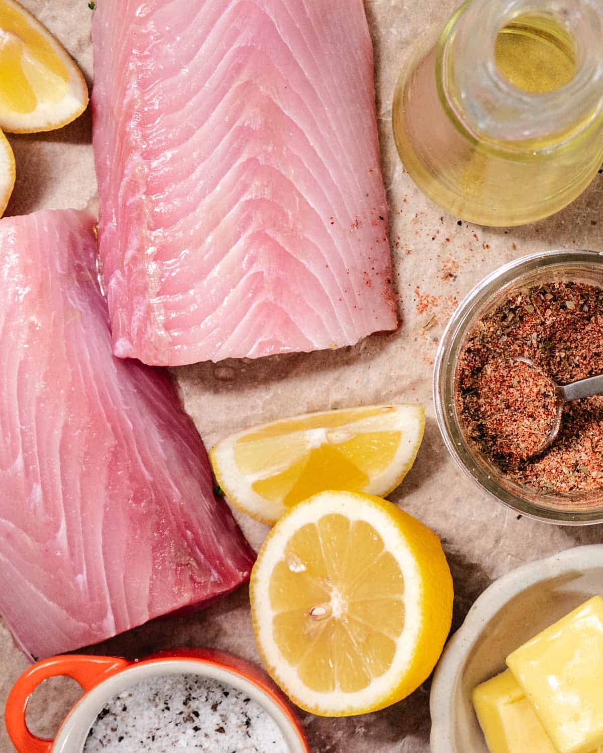 Fresh mahi mahi fillets with blackened seasoning, butter, lemon, and oil on a prep surface