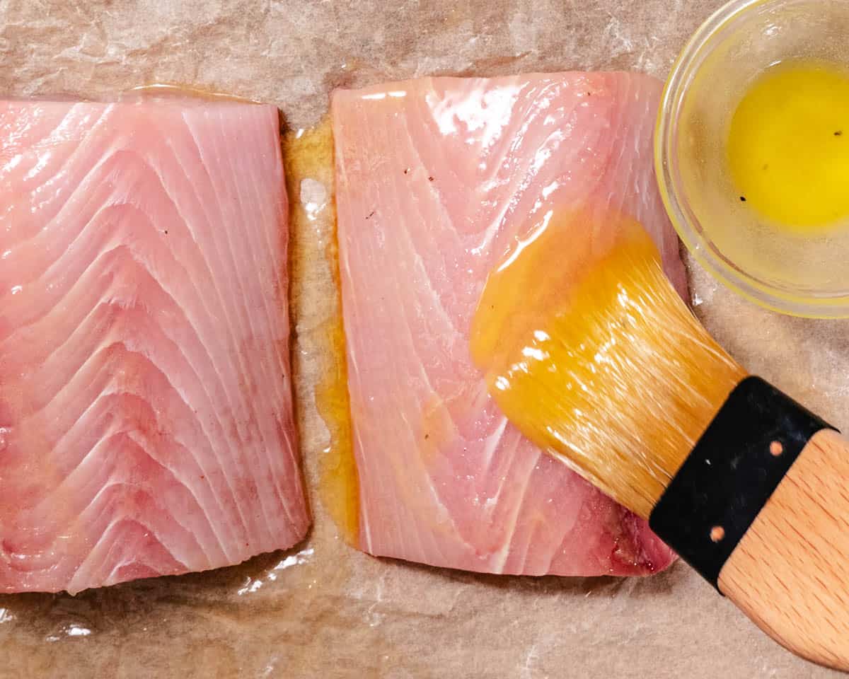 Brushing mahi mahi with melted butter before cooking