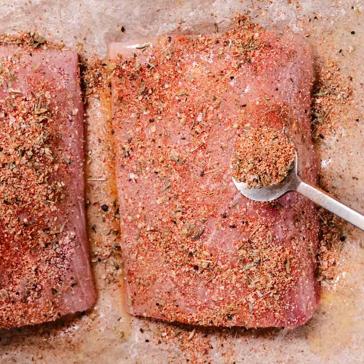spooning Cajun blackened seasoning over mahi mahi