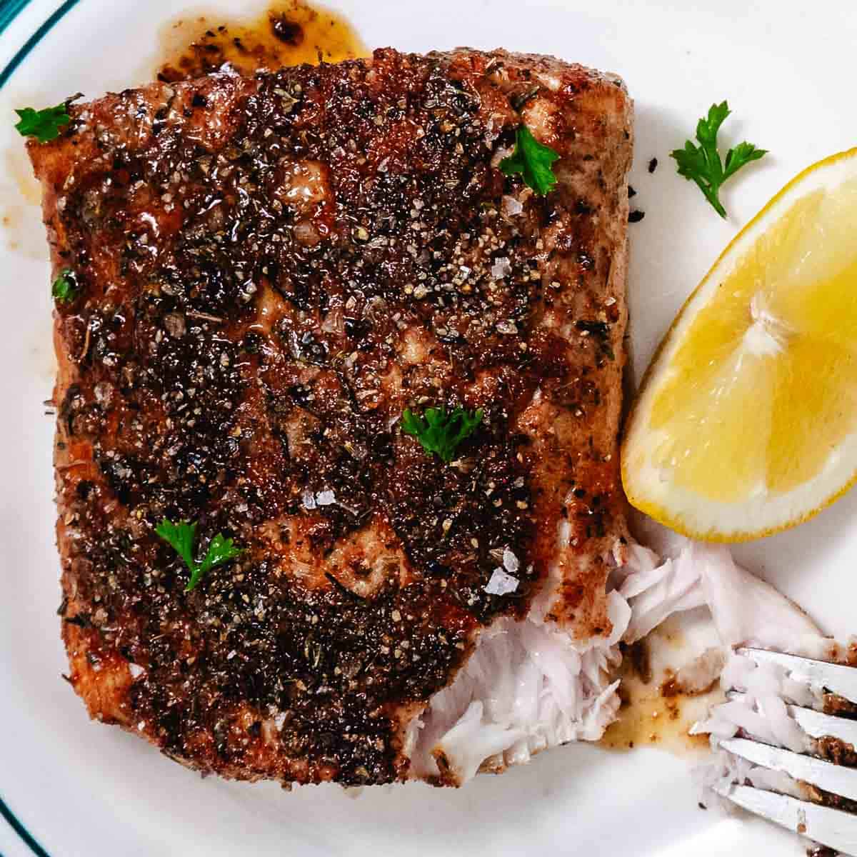 Flaky blackened mahi mahi with a fork showing the moist interior of the fish.