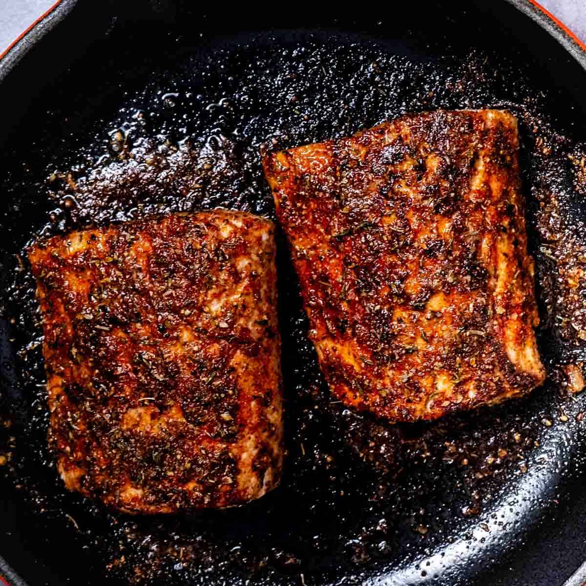 Blackened mahi mahi fillets searing in a cast iron skillet with butter and seasoning