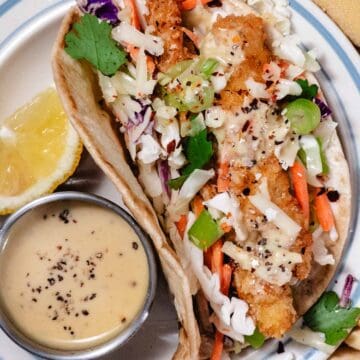 Crispy chicken cutlet wraps with coleslaw mix, green onions, and honey mustard sauce served with a lemon wedge and extra dipping sauce.