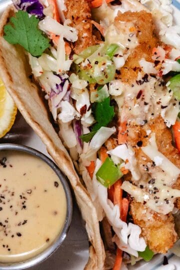 Crispy chicken cutlet wraps with coleslaw mix, green onions, and honey mustard sauce served with a lemon wedge and extra dipping sauce.