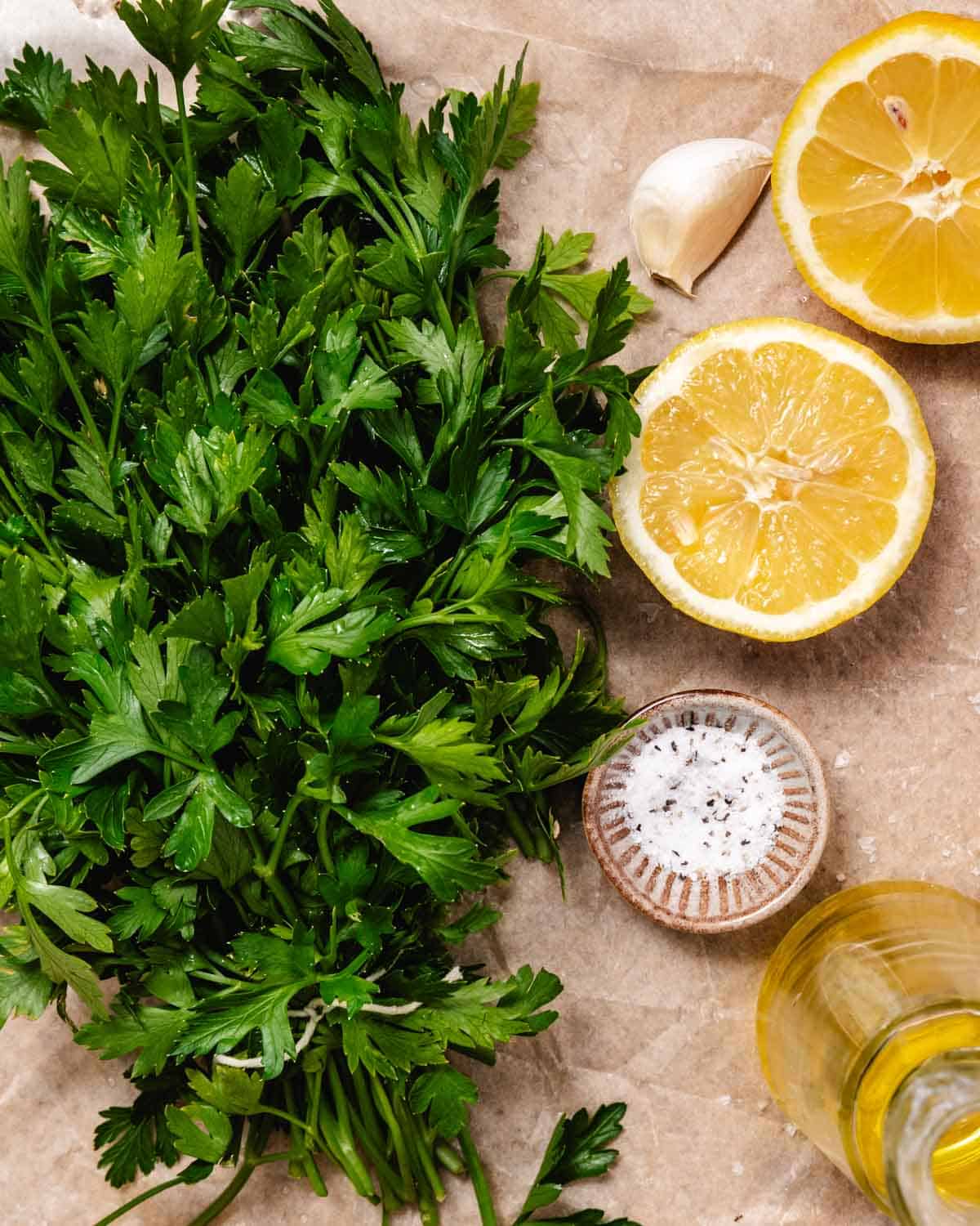 Fresh gremolata ingredients with parsley, lemon, garlic, salt, and olive oil on a board