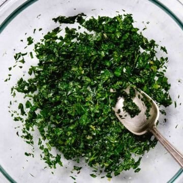 Finished gremolata with parsley, garlic, and lemon zest in a bowl with a spoon ready to serve