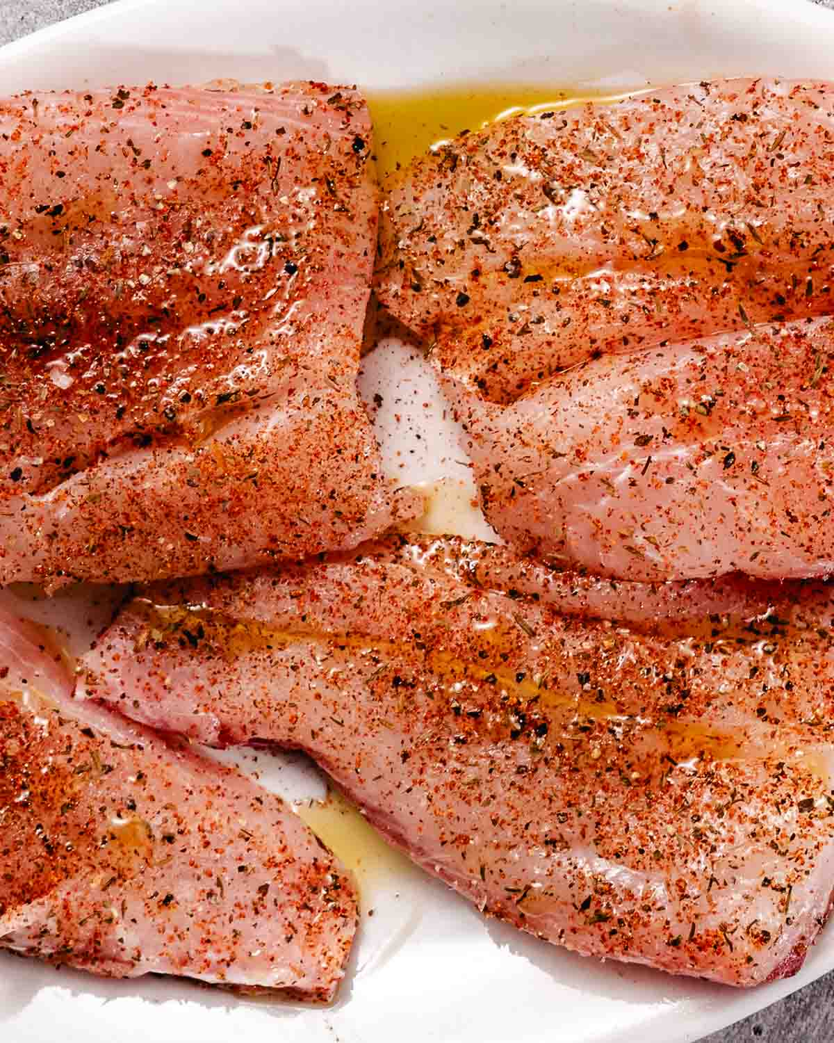 Raw red snapper fillets coated with olive oil and blackened