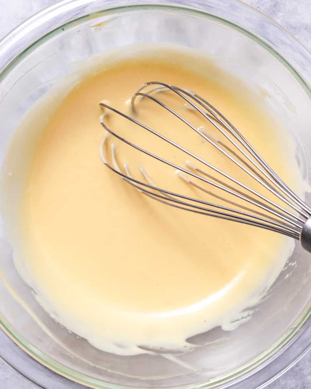 whisking creamy honey mustard dressing in a glass bowl