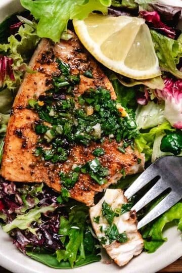 Pan-seared swordfish steaks over mixed green salad topped with chimichurri sauce.