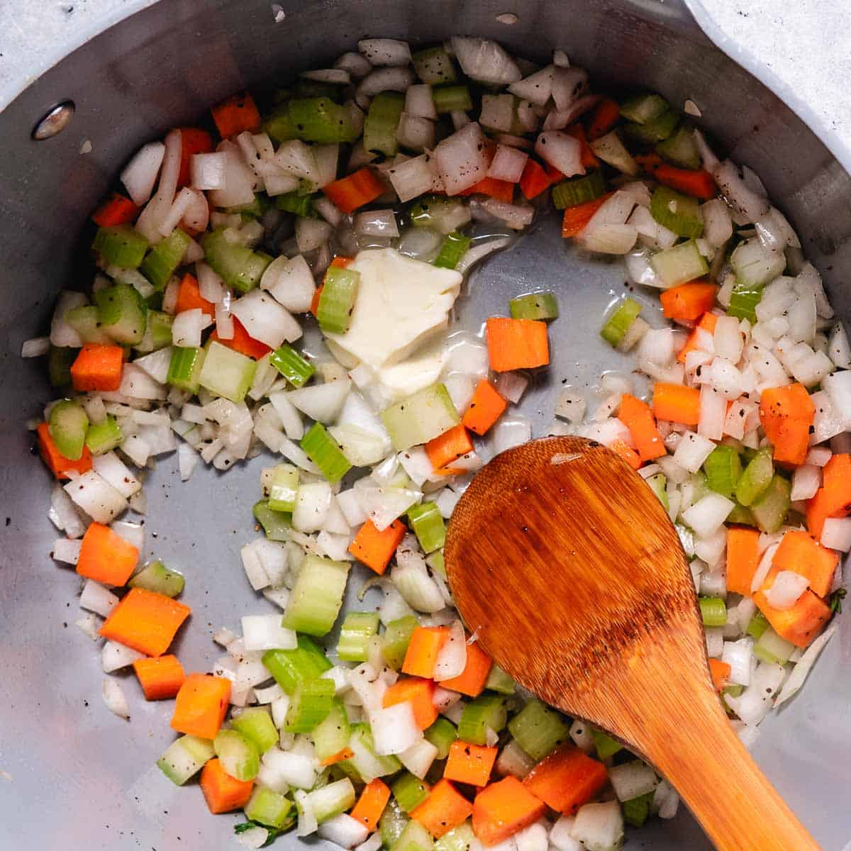 sautéing vegetables in a large pot with butter