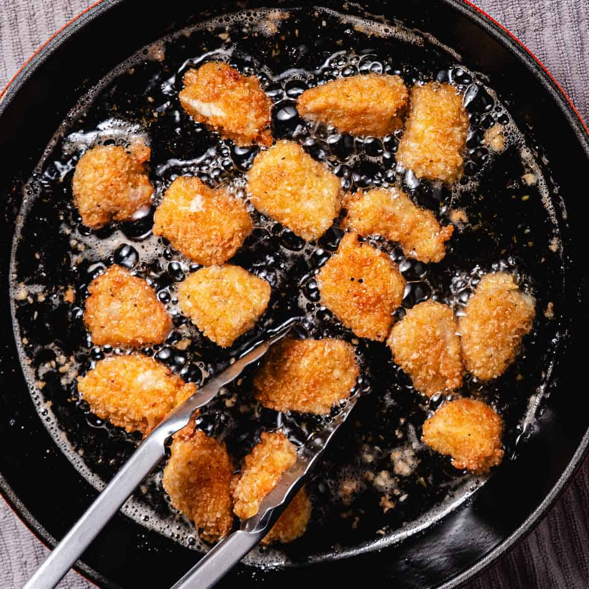 Fruing coconut chicken nuggets in a skillet