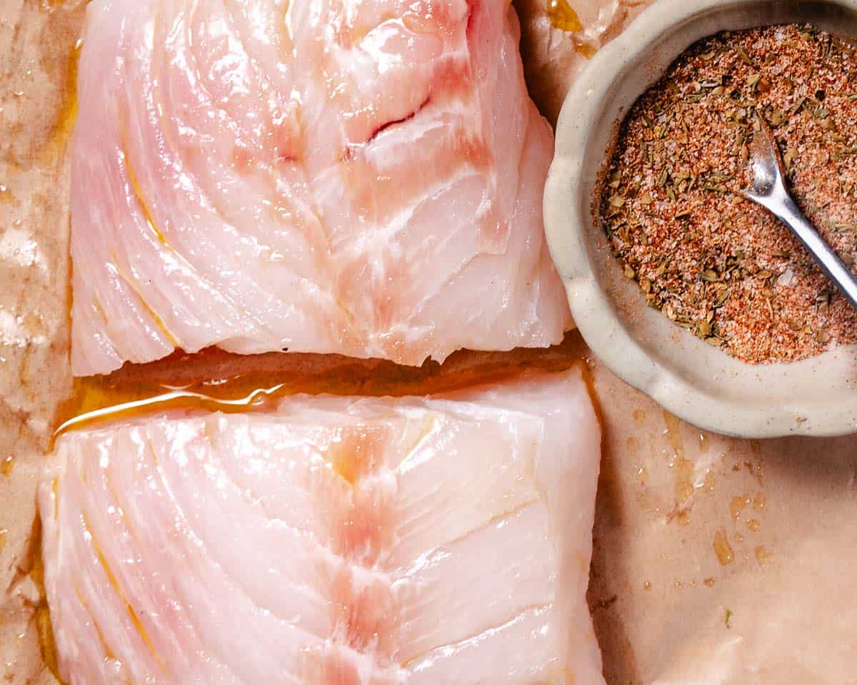 Fresh, moist grouper fillets brushed with olive oil next to a bowl of blackened seasoning.