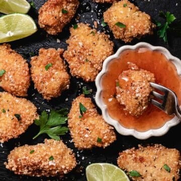 Gluten-free coconut chicken nuggets with sweet chili dipping sauce, lime wedges, and flaky sea salt.
