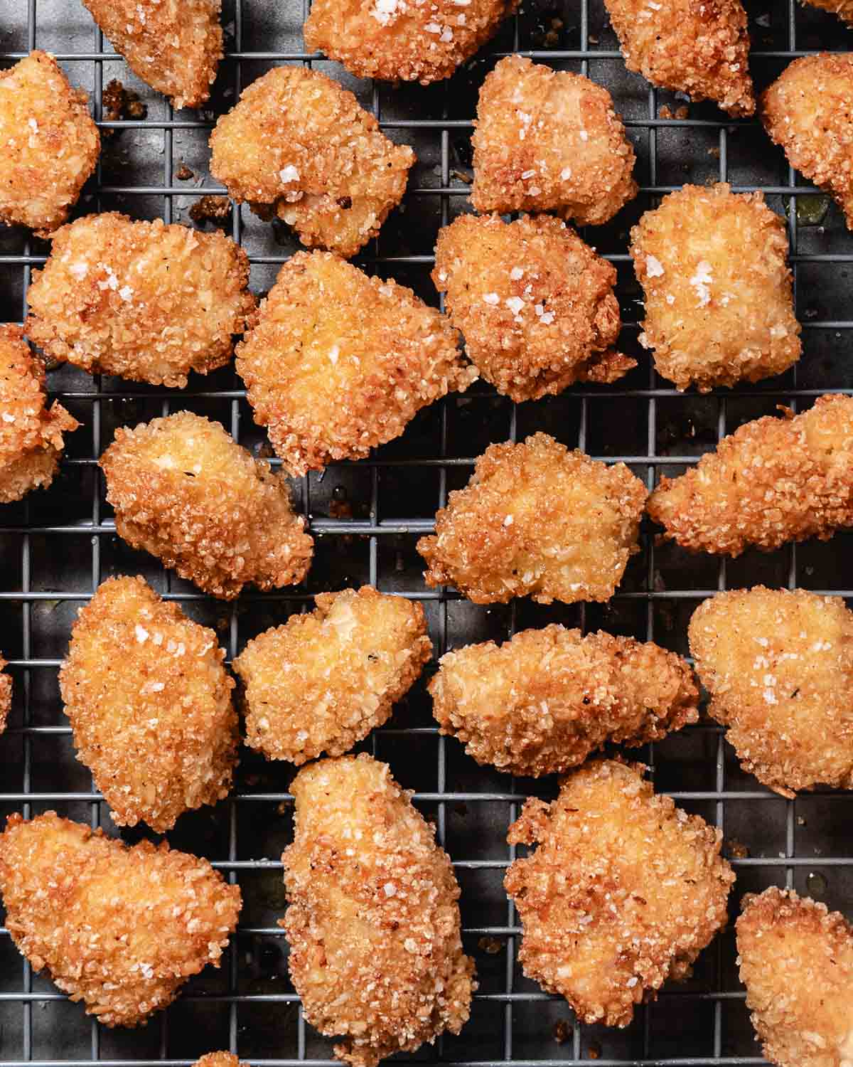 Coconut chicken nuggets on a cooling rack after frying.