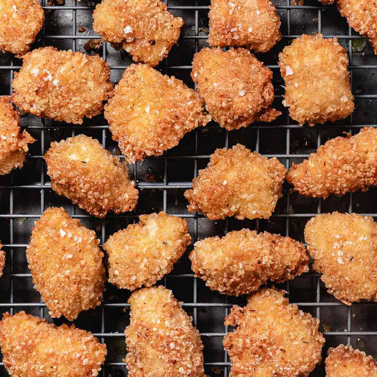 Coconut chicken nuggets on a cooling rack after frying.