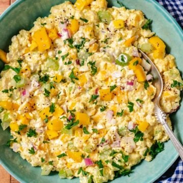Mango egg salad in a green bowl with fresh parsley and black pepper.