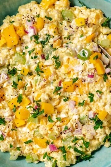 Mango egg salad in a green bowl with fresh parsley and black pepper.