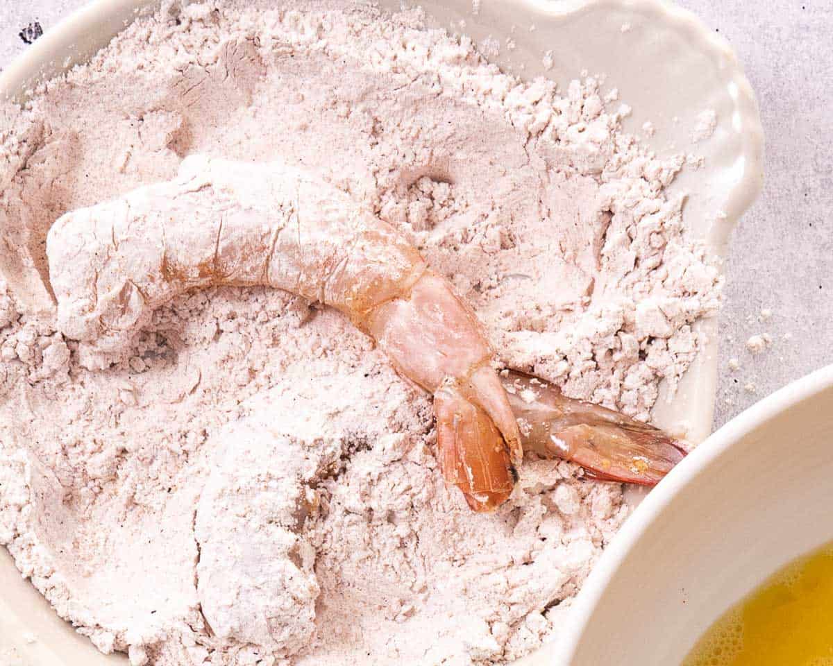 Raw shrimp coated in seasoned cornstarch before dipping in egg wash and coconut flakes.