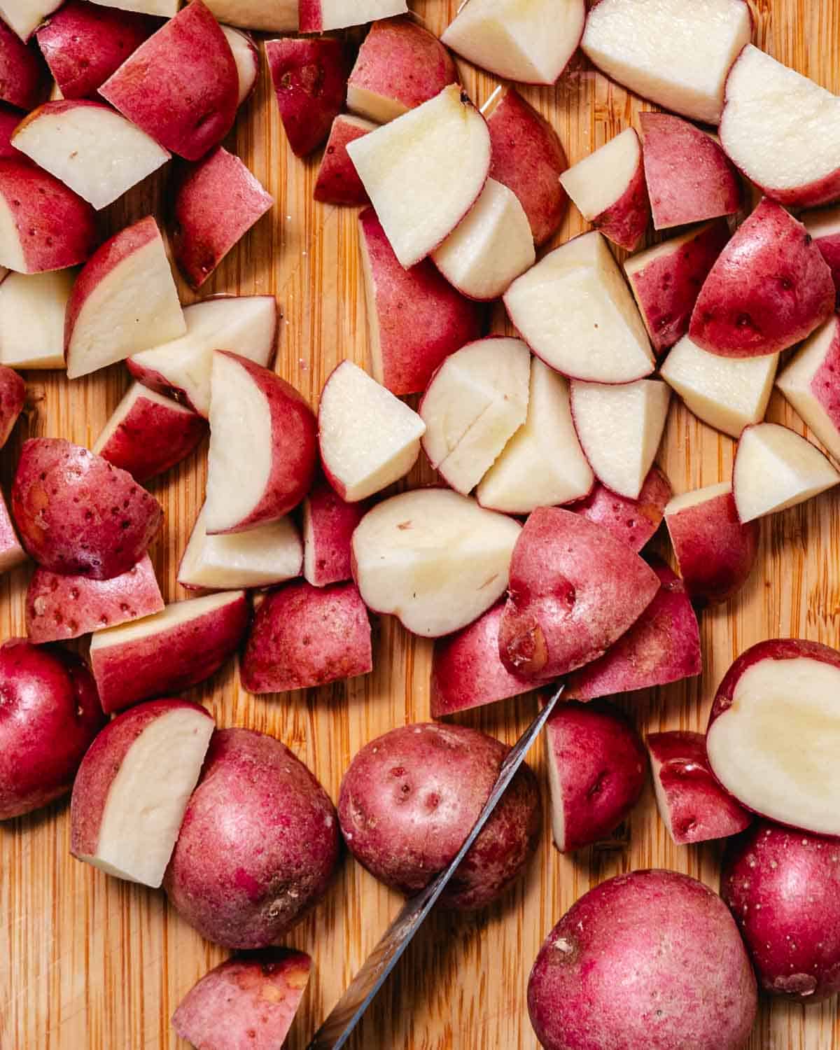 Chopped red potatoes on a cutting board, ready to cook for potato salad.