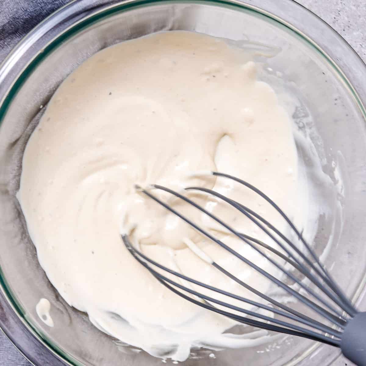 whisking mayo dressing in a glass bowl